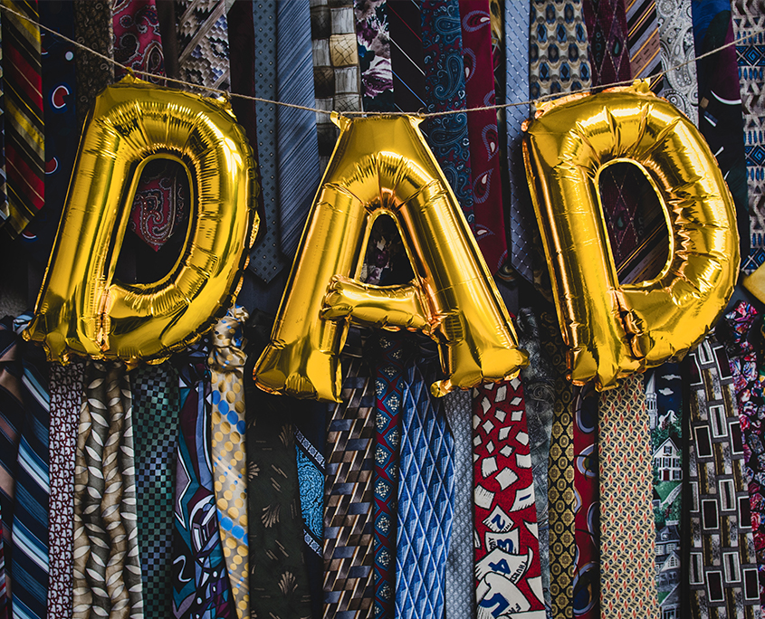 "DAD" Spelled In Balloons In Front of a Wall of Ties